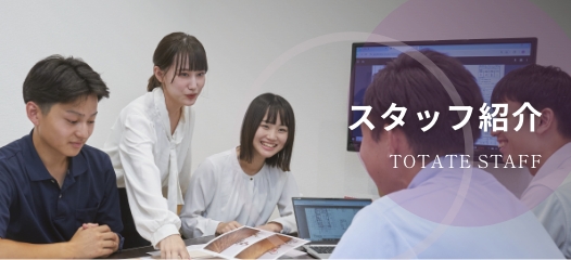 会議中のスタッフの集合写真、テーブルに資料を広げている